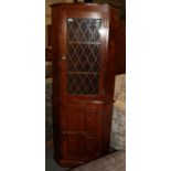 A modern oak standing corner cupboard with lead glazed upper section and panelled lower section,