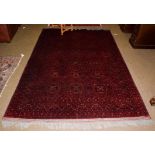 An Afghan Bashir carpet, the deep brick red compartmentalised field enclosed by multiple