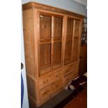 A pine farmhouse kitchen dresser with two large glazed doors, over a base section fitted with four