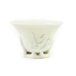 A Chinese Blanc de Chine Libation Cup, 18th century, of ovoid form, moulded with prunus, 9.5cm wide;