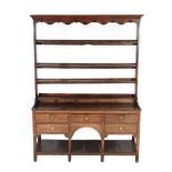 A George III Oak Open Dresser and Rack, late 18th century, the upper section with a wavy shaped