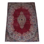 Kirman Carpet South East Iran, circa 1940 The plain raspberry field centred by a floral medallion