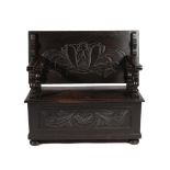 An Early 20th Century Carved Oak Monks' Bench, the pivoting back support above a hinged seat with