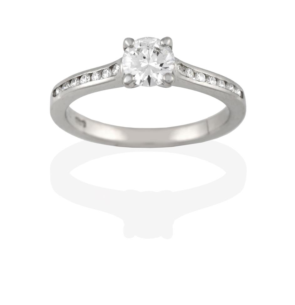 A Platinum Diamond Solitaire Ring, the round brilliant cut diamond in a claw setting, to a channel