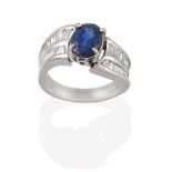 A Sapphire and Diamond Ring, the oval cut sapphire in a white four claw setting, to shoulders