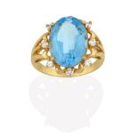 An 18 Carat Gold Blue Topaz and Diamond Cluster Ring, the oval cut blue topaz within a spaced border