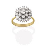 An 18 Carat Gold Diamond Cluster Ring, the round brilliant cut diamond within a double stepped