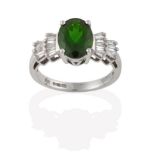 A Diopside and Diamond Ring, the oval cut diopside flanked by stepped tapered baguette cut diamonds,