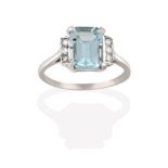 An Aquamarine and Diamond Ring, the emerald-cut aquamarine in a white claw setting, flanked by trios