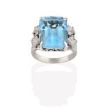 A Blue Topaz Ring, the emerald-cut blue topaz in a white four claw setting, to textured foliate