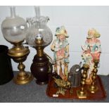 A pair of coloured bisque figures, two oil lamps, painted lacquer bucket, Romanesque oil lamp and