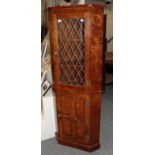 A modern oak standing corner cupboard with lead glazed upper section and panelled lower section,