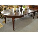 A mahogany wind out dining table raised on tapering reeded legs with three additional leaves,