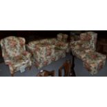 A pair of floral upholstered wing back arm chairs; together with a three-seater sofa and pair of