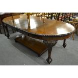 An extending mahogany dining table with three additional leaves raised on ball and claw feet