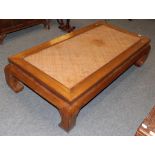 A 20th century Chinese hardwood coffee table with a rattan top, 166cm wide by 86cm deep by 42cm