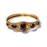A garnet hinged bangle, five graduated oval cabochon garnets in yellow rubbed over settings to a