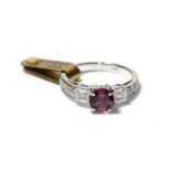 A tourmaline and diamond ring, the round cut pink tourmaline flanked by trios of baguette cut