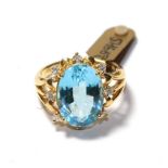 An 18 carat gold blue topaz and diamond cluster ring, the oval cut blue topaz within a spaced border