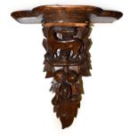 An Edwardian carved oak wall bracket, surmounted by a stag and decorated with leaves, 48cm by 24cm