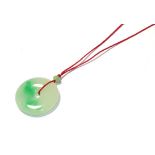 A circular jade pendant, on a red cord necklace, pendant measures 3.7cm diameter . Gross weight 16.7