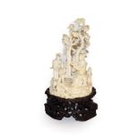 A Japanese Meiji period carved ivory okimono on a hardwood stand, formed as a group of figures on a