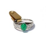 An emerald and diamond ring, the cabochon emerald in a white collet setting, to shoulders inset with