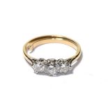 A diamond three stone ring, the graduated round brilliant cut diamonds in white claw settings, to