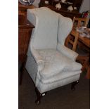 A Georgian style upholstered wingback armchair raised on cabriole legs