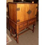 An oak cocktail cabinet raised on turned baluster supports with H-stretcher, 100cm by 52cm by 140cm