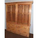 A pine farmhouse kitchen dresser with two large glazed doors over a base section fitted with four