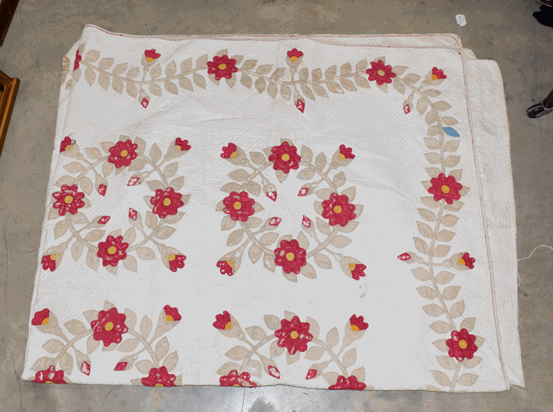 A late 19th century white cotton quilt, decorated with circular floral garlands of red flower