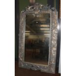 A large imposing parcel gilt mirror with scrolling open work pediment and further scroll work to the