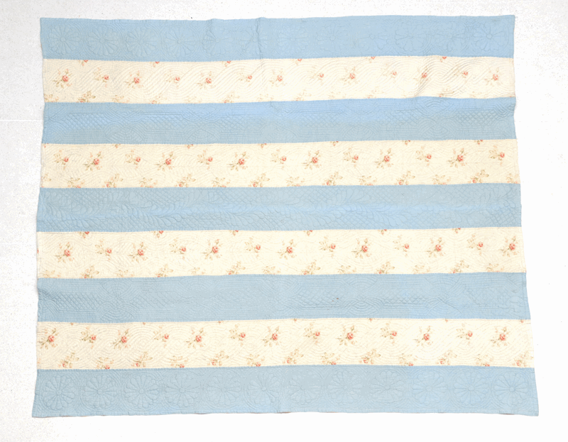 A late 19th century stripy quilt comprising pale blue and floral stripes to one side, yellow ochre