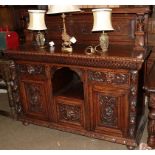 A Gothic revival carved oak sideboard, ornamented with masks and ecampus scrolls, 154cm by 57cm by