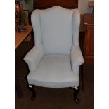 A Georgian style upholstered wingback armchair raised on cabriole legs