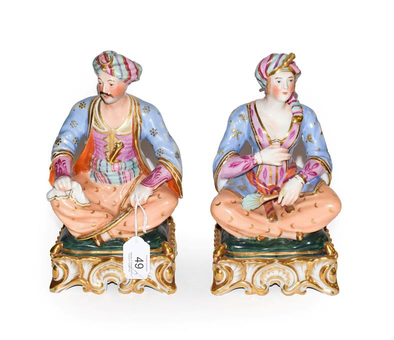 A pair of Paris porcelain figures formed as a seated Turk and his companion, raised in gilt Rococo