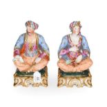 A pair of Paris porcelain figures formed as a seated Turk and his companion, raised in gilt Rococo