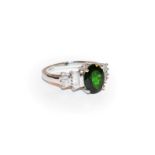 A diopside and diamond ring, the oval cut diopside flanked by stepped tapered baguette cut diamonds,