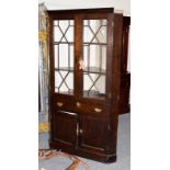 A mid 18th century oak free-standing corner cupboard, the moulded cornice above astragal glazed