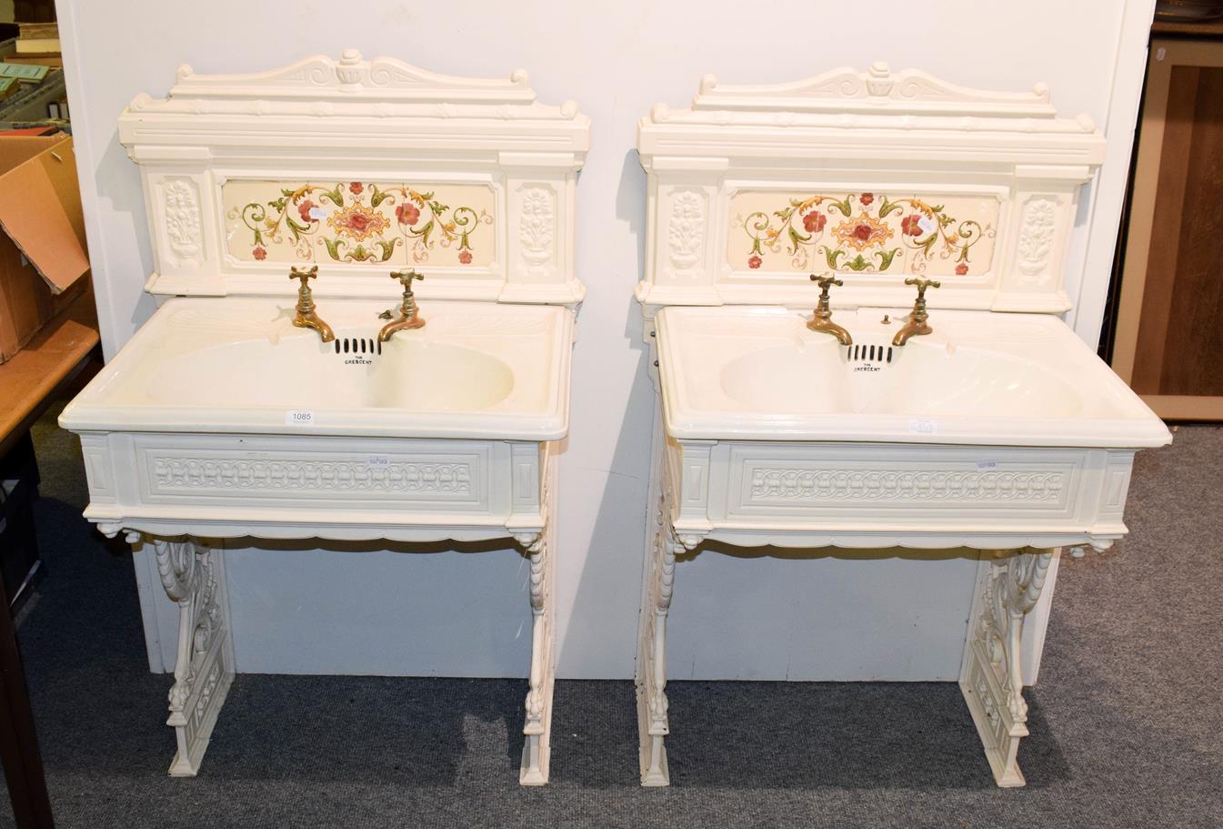 A pair of Victorian ladies and gents wash basins on painted cast iron stands with tiles splash-backs