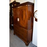 An early 19th century mahogany dwarf linen press, panelled top section raised over a chest base on