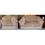 A chenille upholstered two-seater settee with bolster cushions and in stylized floral design,