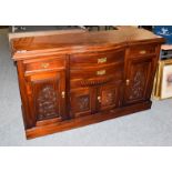 A reproduction bow fronted sideboard with stained finish and carved panels, 157cm by 54cm by 94cm