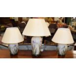 Three decalomania glass table lamps decorated with irises, comprising a pair 26cm and a larger