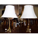 A pair of gilt brass table lamps, the tapering reeded supports on hipped legs and paw feet, height