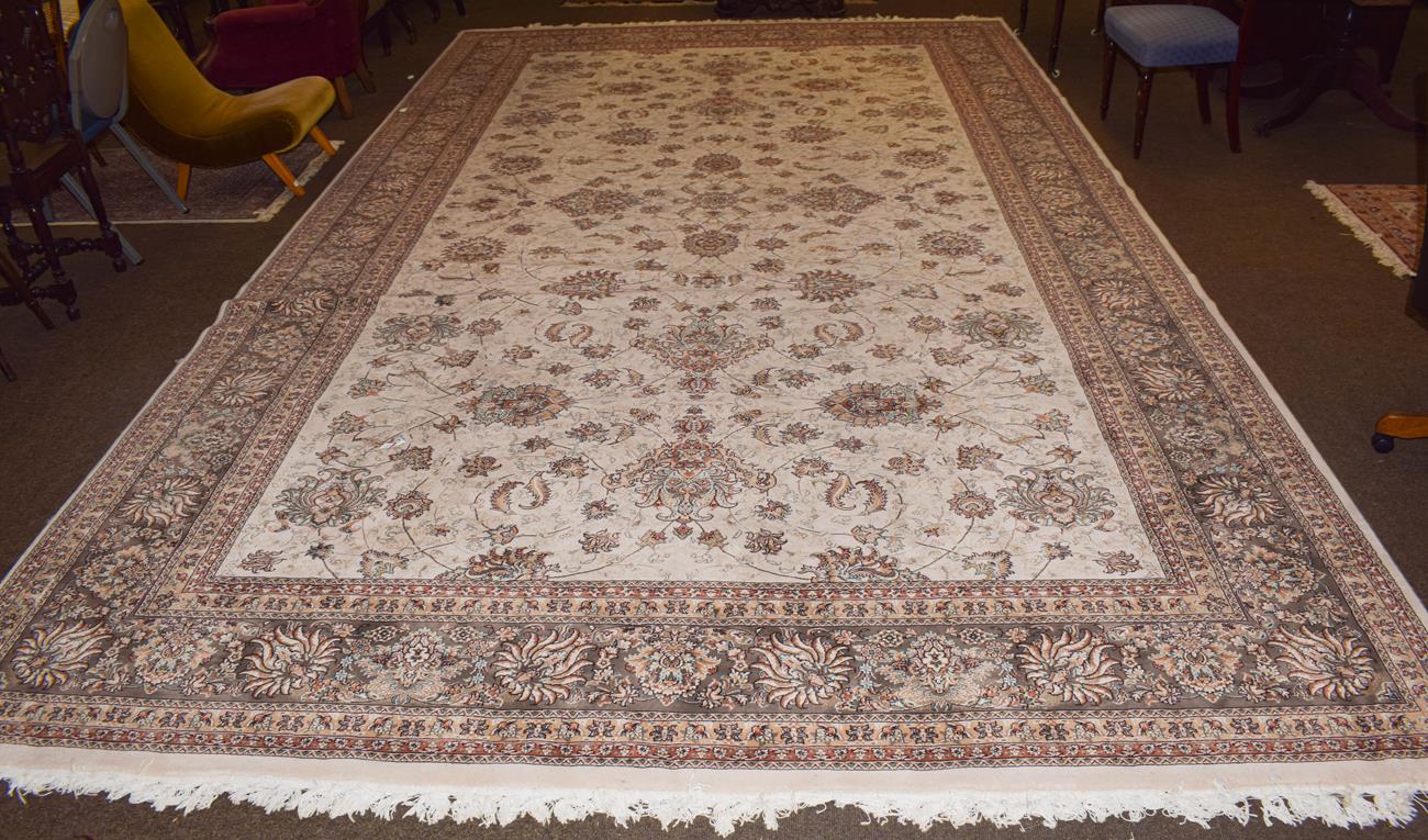 A large machine made carpet of oriental design, the cream field with an all over design of palmettes