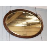 An Arts & Crafts oval planished copper wall mirror, 83cm by 58cm