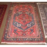 A Hamadan rug, the tomato red field with serrated medallion framed by leaf and calyx borders,