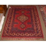 A machine made rug, the deep brick red field with hooked central gul, 168cm by 141cm